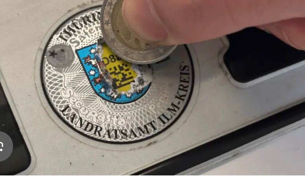 Sicherheitscode unter der runden Stempelplakette freikratzen